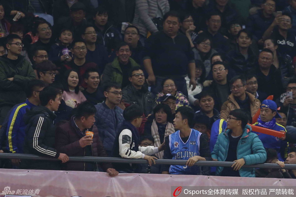 几名工作人员紧紧抱住一名情绪激动的球迷，另一名安保人员则奋力推开纠缠的人群，冲突逐渐得到控制