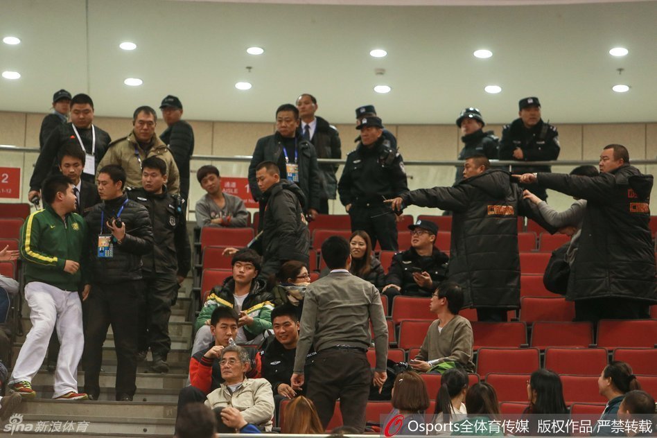 五棵松体育馆内人声鼎沸，但看台上紧张的气氛一触即发，部分球迷情绪激动地站起身，手势激烈地指向场地中央，周围的安保人员神情严峻，迅速向事发区域靠拢，试图在冲突升级前进行干预。