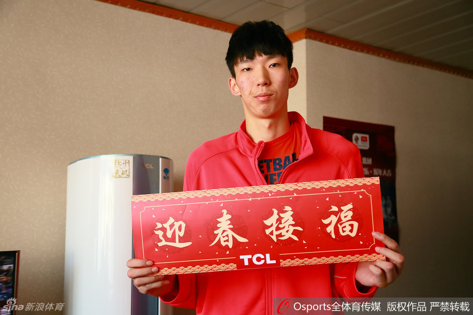 周琦身着白色训练服，面对镜头露出标志性的腼腆笑容，他双手抱拳向小球迷作揖拜年，眼神中满是大哥哥般的温柔与亲切。