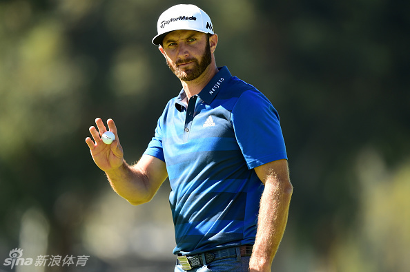 简森·科克拉克在果岭旁精心擦拭手中的高尔夫球，为下一击做足准备