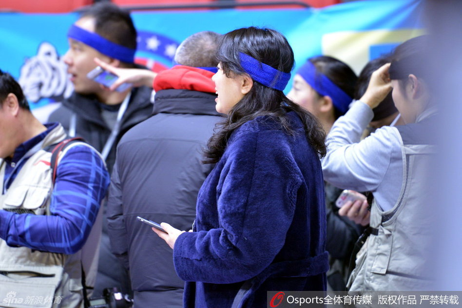 一名戴着发带的记者正低头专注地用手机发着信息，似乎正在向后方的编辑部传递着赛场内这一独特的风景线，将无声的抗议通过电波传向远方。