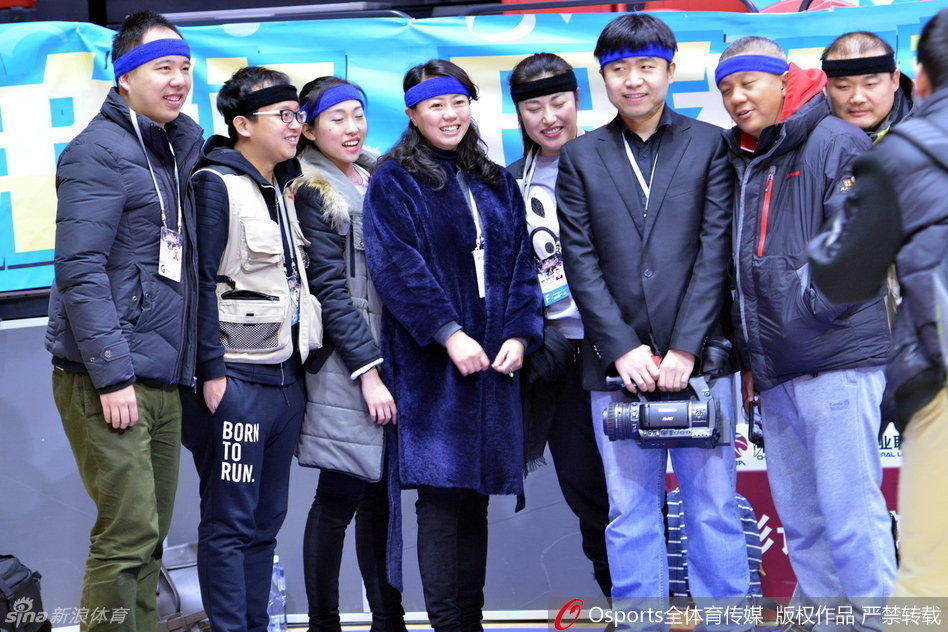 乌鲁木齐红山体育馆内，几位佩戴着蓝色发带的媒体老师正全神贯注地调试着手中的长枪短炮，额间的发带在紧张的赛场氛围中显得格外醒目，仿佛一种无声的誓言。