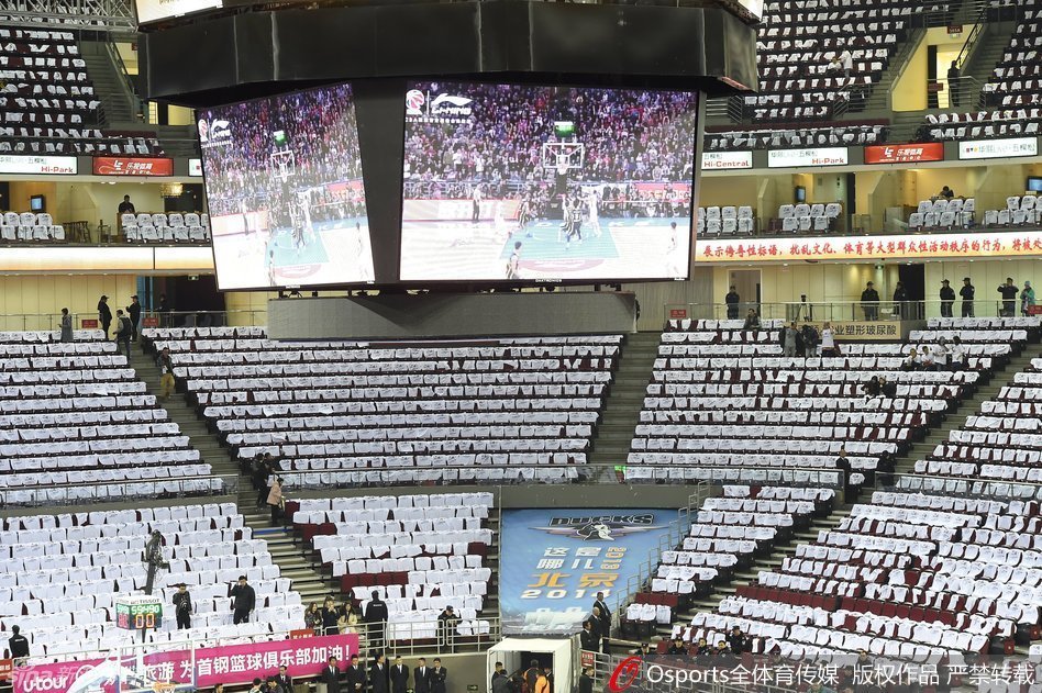 球迷们手持白色助威衫陆续入场，现场气氛热烈，但部分座位因助威衫被收走而出现了颜色不一的缺口。