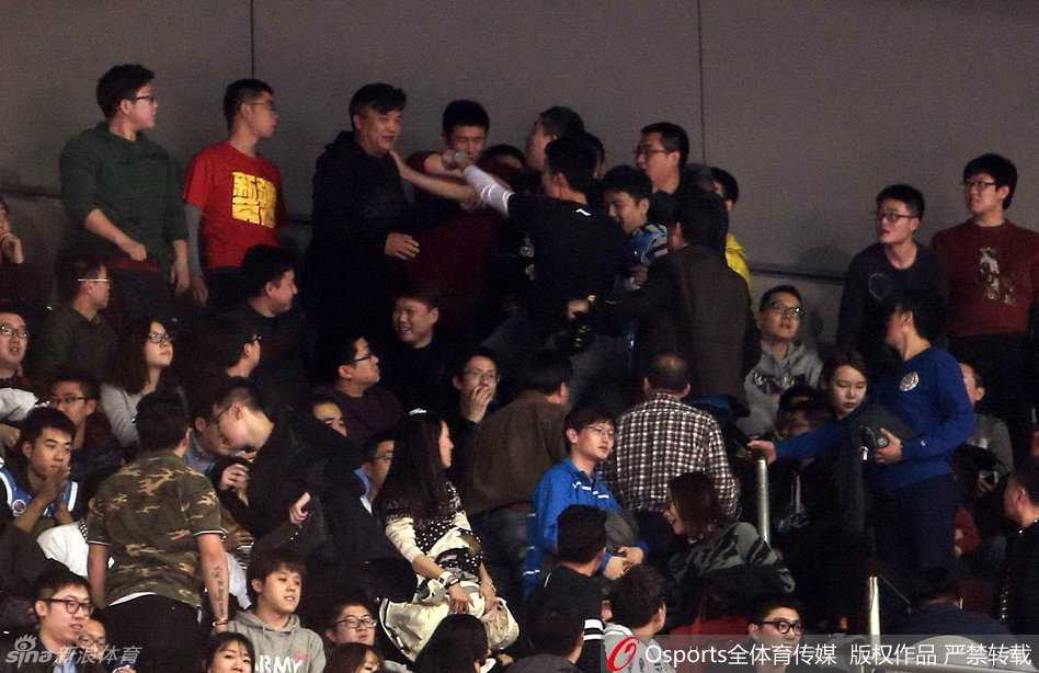 一名身着灰色安保制服的工作人员在混乱中面容严峻，他张开双臂试图拦住身后汹涌的人群，而在他的前方，是密密麻麻举起手机拍摄现场的围观群众。