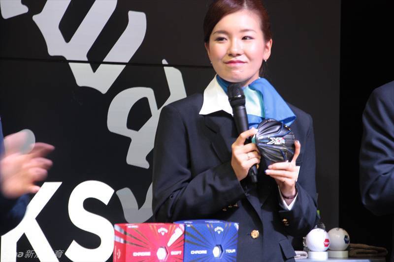 藤田光里站立于活动现场中央，聚光灯下，她身姿挺拔，面容姣好，展现美女球手的自信风采