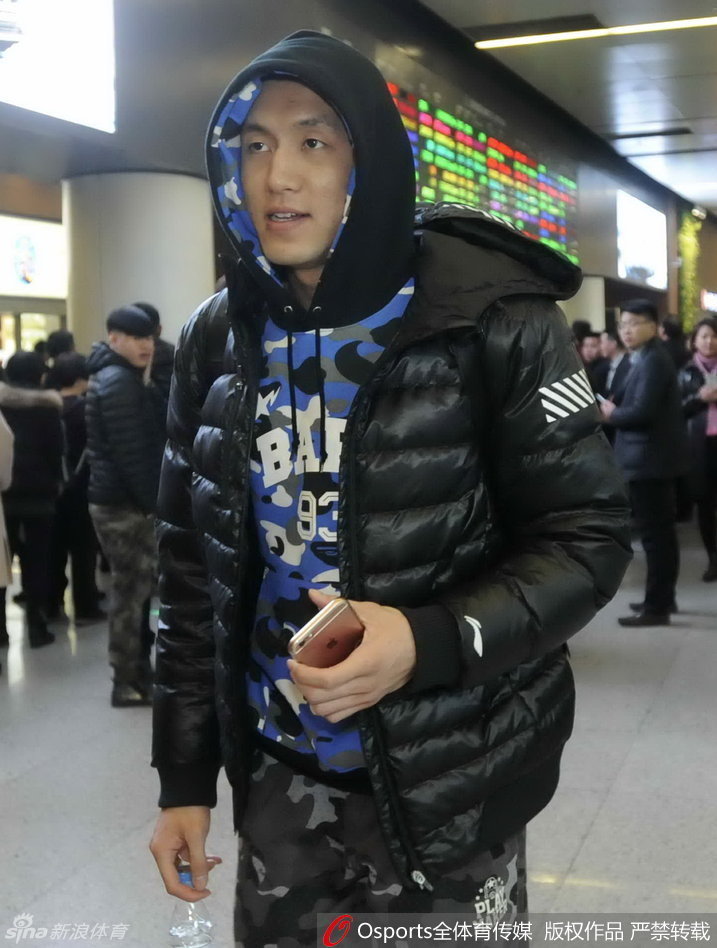 一位年轻的辽宁女球迷高高举着一块手绘的白色标语牌，上面用彩色画笔写满了对辽宁男篮的支持话语，她踮起脚尖，眼神中满是期盼，努力让自己准备的标语能被球员们看见。