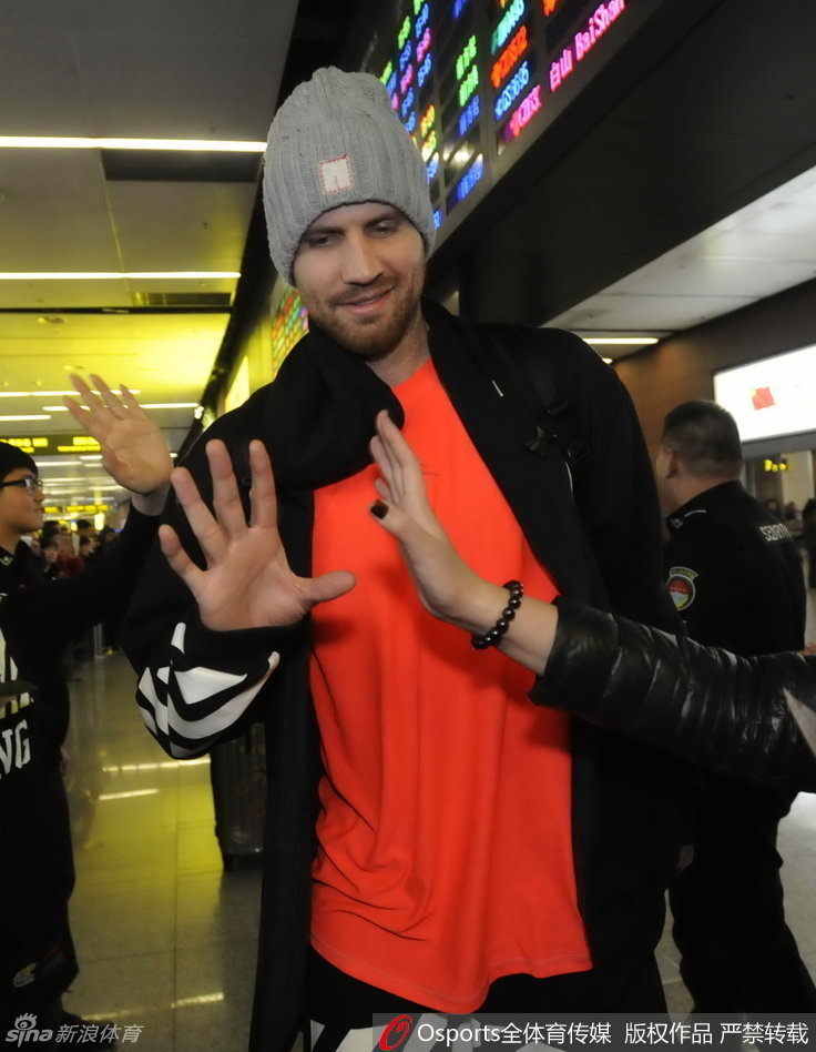 队长杨鸣被球迷团团围住，他耐心地停下脚步，微低着头为身边的球迷签名，周围球迷的脸上洋溢着幸福的笑容，纷纷用手机记录下这难得的近距离接触时刻。