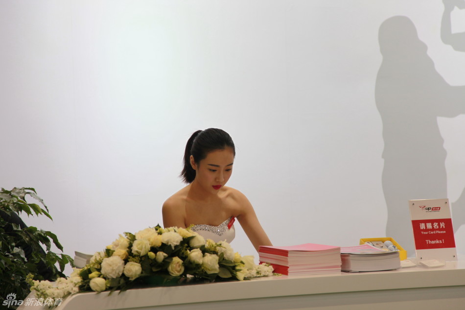 展厅内，一位美女助手正俯身细心调试高尔夫推杆，动作娴熟，展现出幕后工作的专注与细致