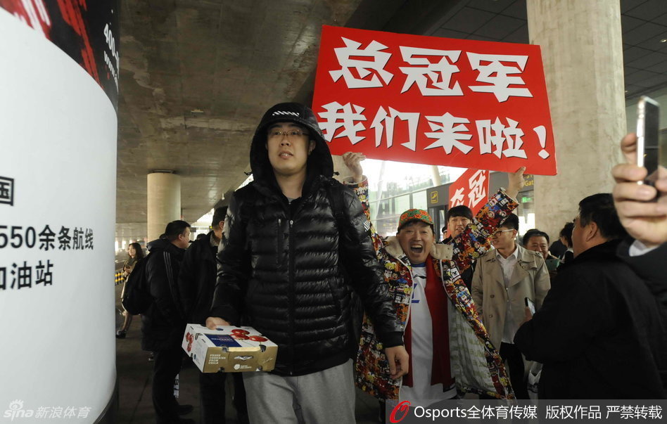 功勋外援哈德森与兰多夫享受着球迷的欢呼，边走边用手机记录这难忘的接机盛况。球迷们伸出手臂，只为与心中的英雄击掌庆贺。