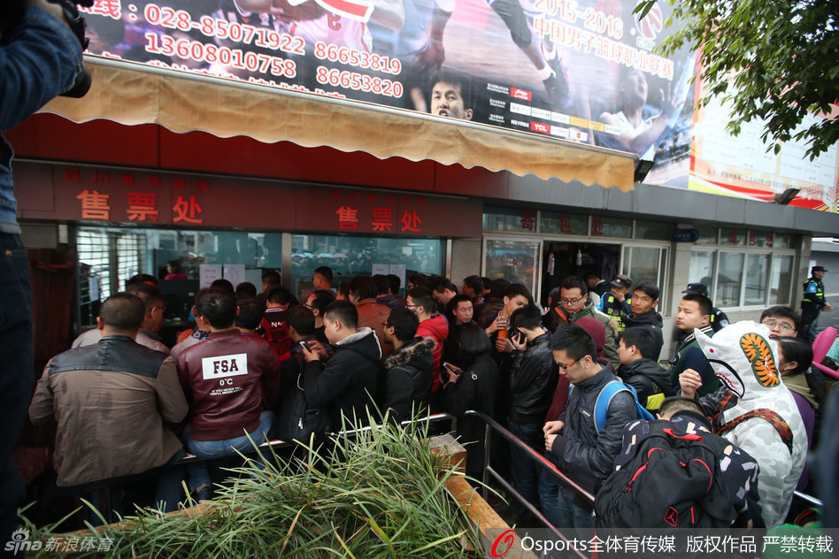 画面中可见购票长龙一眼望不到头，球迷们自备的各种小板凳和瑜伽垫在队伍旁一字排开，大家一边聊天一边耐心等待着清晨的开票时刻。