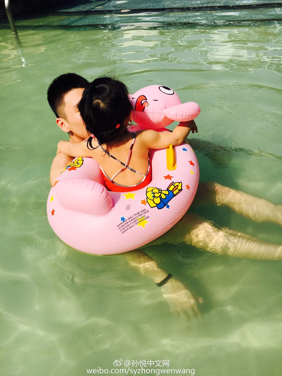 小月亮独自坐在卡通游泳圈中漂浮在水面，孙悦在不远处微笑守护，画面宁静温馨