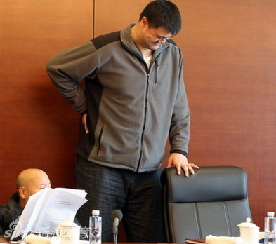 姚明在众人注视下缓缓从大号座椅上站起，高大的身影在严肃的会场中格外醒目，他正走向那把等待着他的普通椅子。