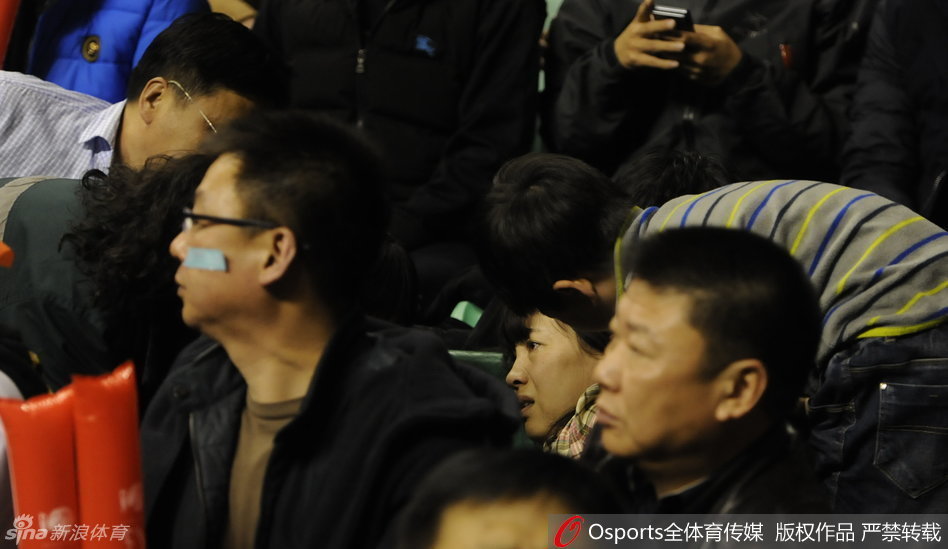 在众人的惊呼与帮助下，晕倒的女球迷在同伴的搀扶下艰难地试图撑起身体，但身体的极度不适让她的动作显得异常吃力。