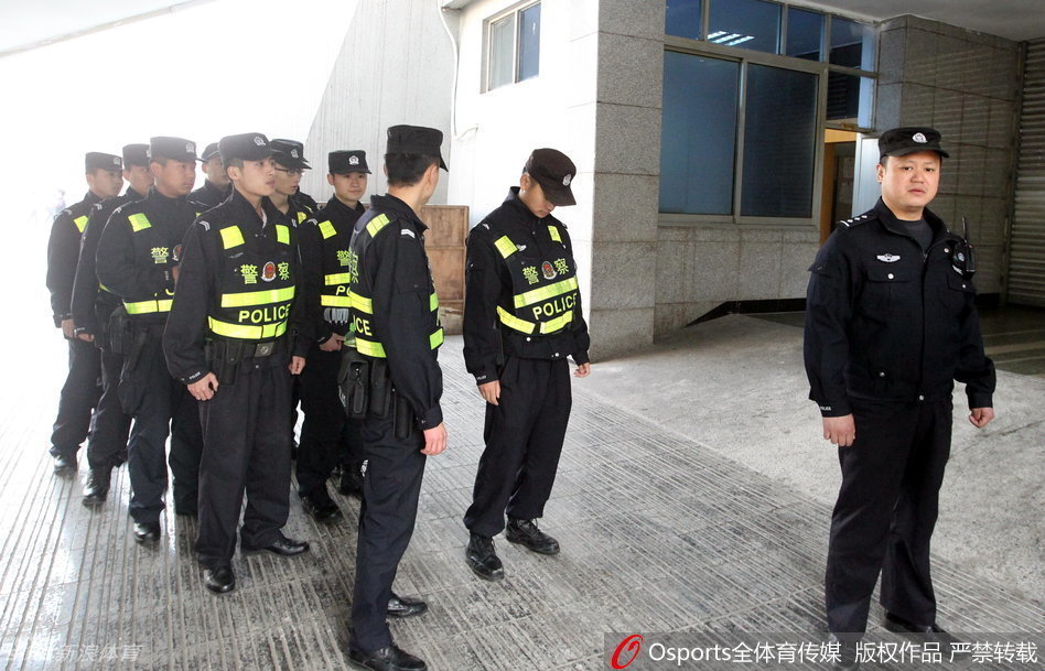 杨学增指导在人群缝隙中侧身回望，身后的背景是无数记者模糊的脸和伸出的录音笔，这一瞬间定格了总决赛期间场外的喧嚣与纷扰。