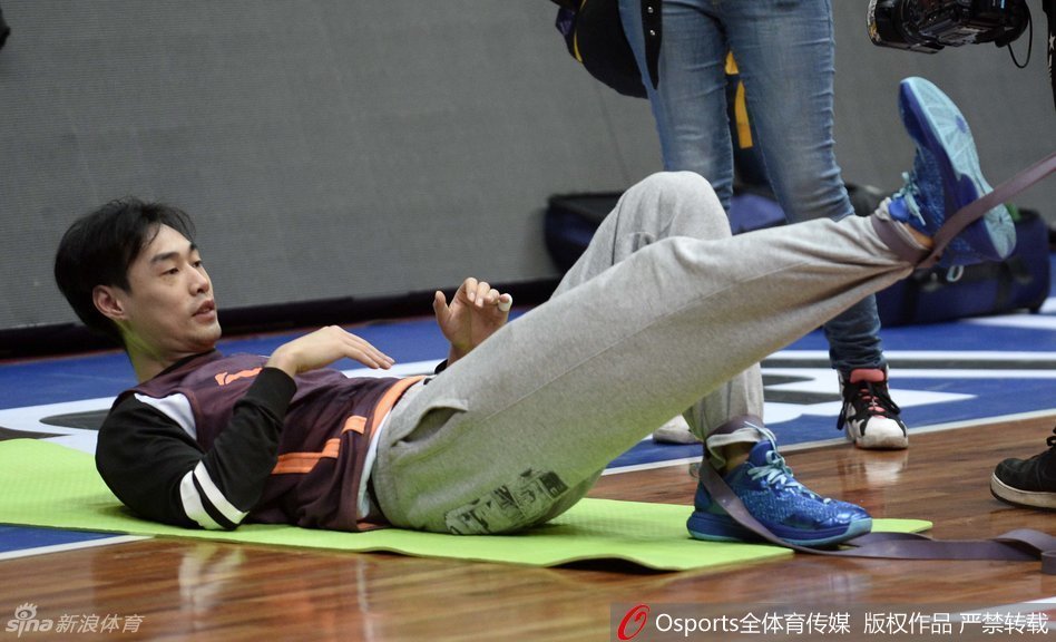 杨学增指导双手交叉抱在胸前，静静地站在场边注视着球员们的上篮训练，目光深邃而平和，仿佛整个球馆的节奏都尽在他的掌握之中