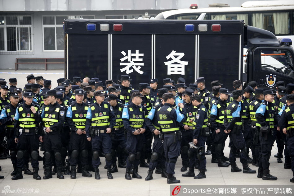 体育馆入场口，数名身穿统一制服的安保人员站成一排，他们手挽手形成一道人墙，有序地疏导着潮水般涌来的观赛球迷。