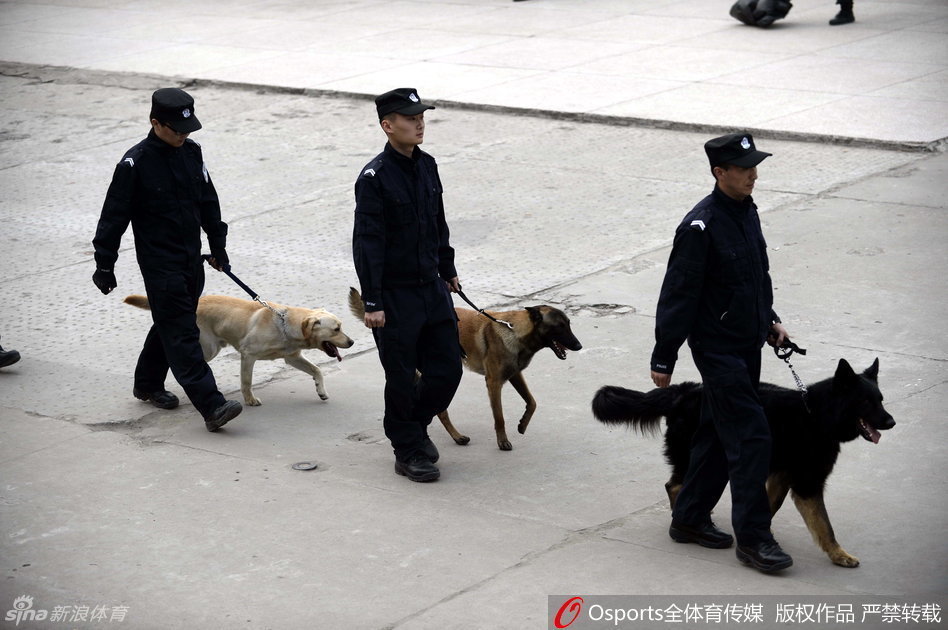 一辆巨大的水炮车静静停靠在体育馆外围的指定位置，巨大的轮胎和车身上的警示标志彰显着它的力量，它是维持场外秩序的终极后盾。
