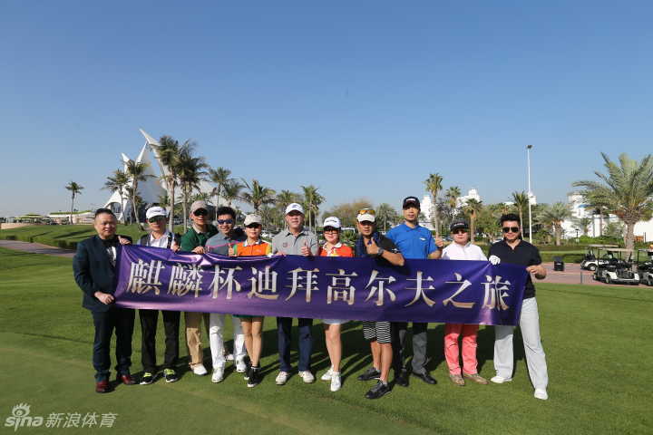 张连伟在迪拜赛场笑容满面，手握球杆准备开球，背景是标志性的沙漠球场与蓝天