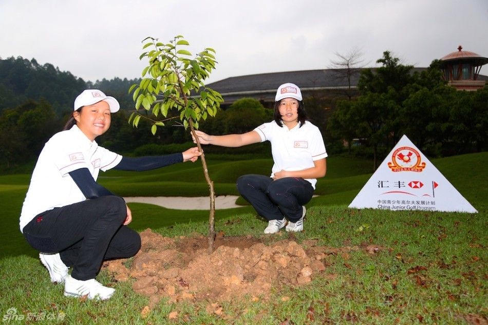 两位小球员合力提着一只水桶，正准备为他们共同栽种的爱心小树苗浇下清澈的定根水。