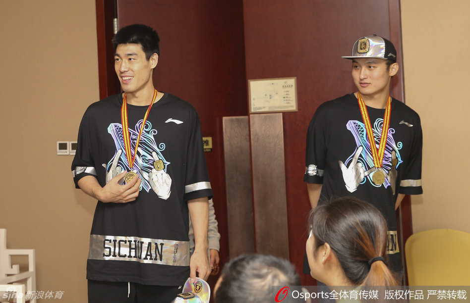 孟达与队友并肩而立，三人胸前的金牌在闪光灯下交相辉映，他们的笑容中充满了兄弟般的情谊和作为冠军队成员的自豪。