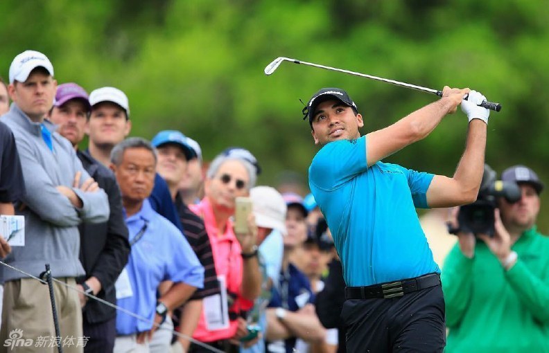 简森·戴伊在果岭上专注凝视，他身后是广阔的球场与竞争的烽火，冠军的气质在沉稳的姿态中流露无遗。