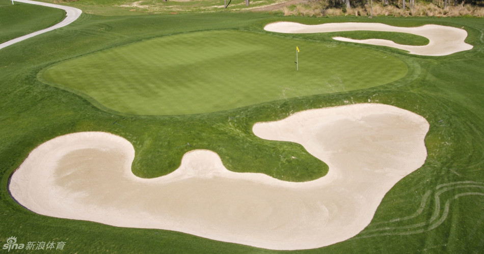 球员在第五洞果岭边细心观察推杆路线，专注的神情与身后静谧的湖泊构成和谐画面