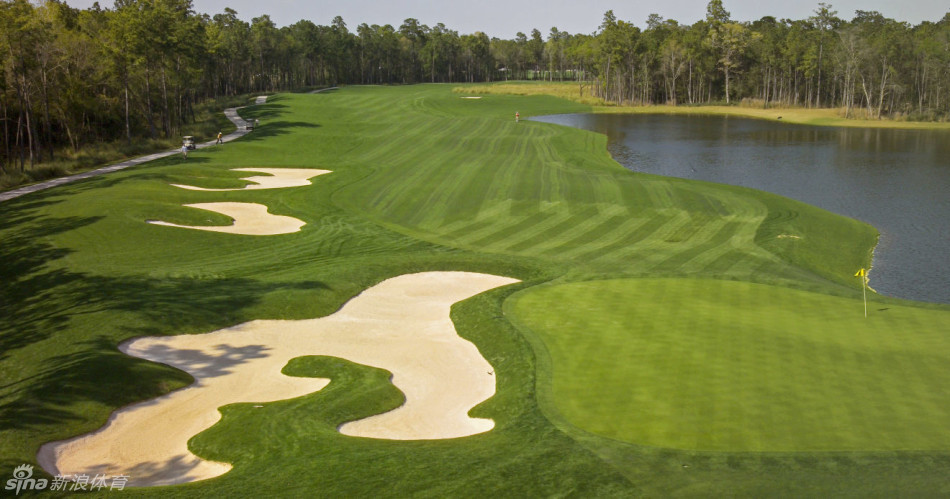 第十一洞水障碍倒映着蓝天白云，选手正谨慎选择球杆，水面泛起涟漪如同此刻观众的心情