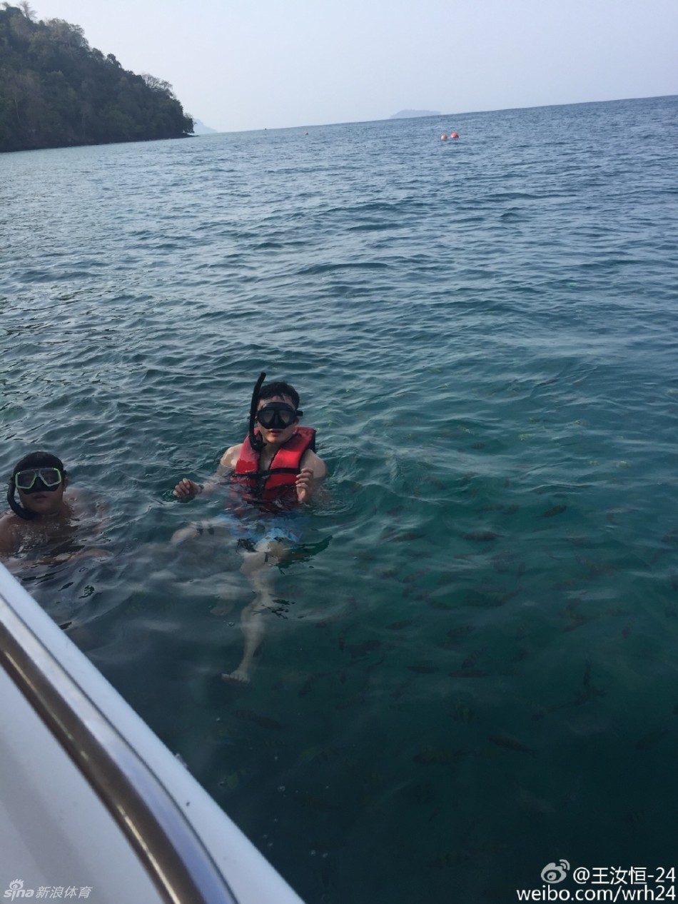 王汝恒身穿潜水服浮在海面，对着镜头比出胜利手势，蔚蓝海水映衬着他的好心情