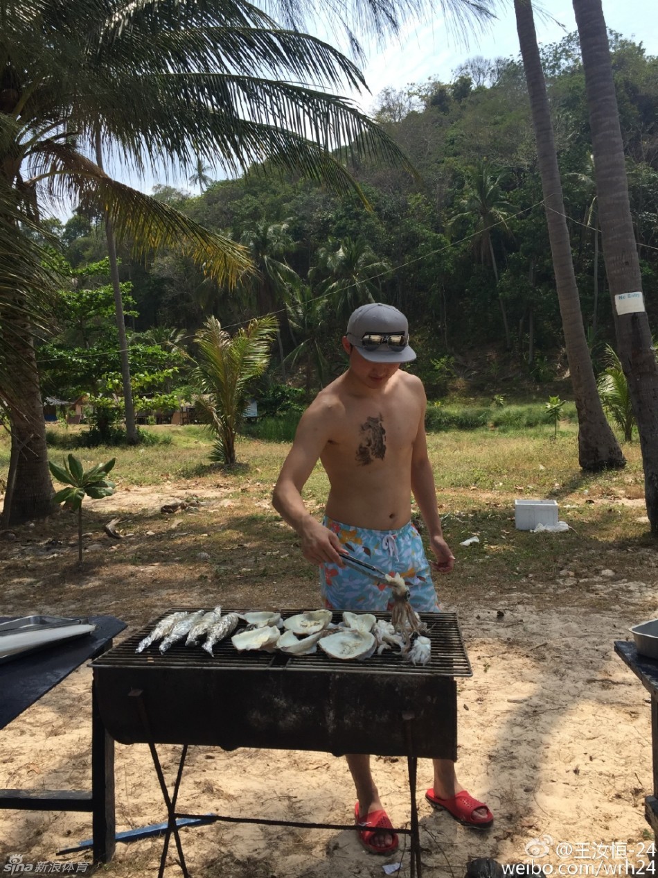王汝恒专注地翻转着烤架上的大虾和扇贝，炭火升腾起烟雾，海鲜烧烤大餐正在进行
