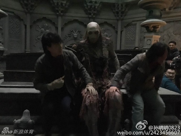 片场休息时的孙明明，还没来得及卸下身上厚重的‘红犼’戏服。在春日暖阳的照射下，这具在古墓中本应不见天日的恐怖丧尸，却惬意地坐在小板凳上晒太阳，巨大的身躯与脚下小小的板凳形成鲜明对比，形成了一种极具冲击力的魔幻现实感。