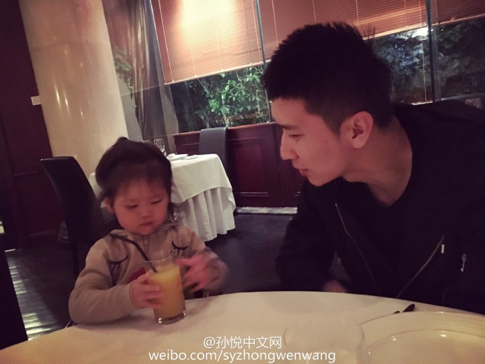 孙悦惬意地坐在遮阳伞下休息，小月亮则乖巧地坐在父亲身边，自己动手享受着美味的食物，孙悦的目光始终温柔地追随着女儿的一举一动，享受着这片刻的宁静与美好。