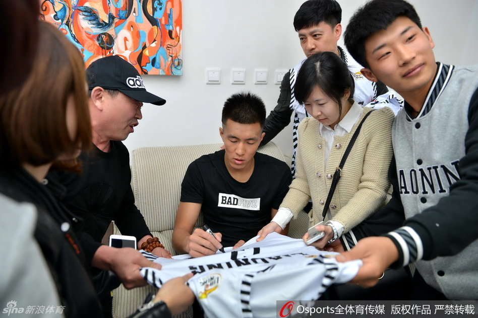 郭艾伦坐在休息区的椅子上，耐心地给一位小球迷递过来的球衣签名，他低垂着眼帘，神情专注，小球迷则在一旁紧张又期待地看着。