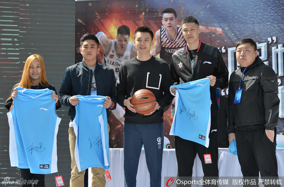 杨鸣低头为热情的球迷认真签名，笔尖划过篮球与照片，专注的神情透露出他对每一位支持者的尊重与珍视。