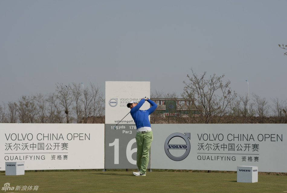 汤榕健在开阔的球道上优雅挥杆，背景是蓝天与绵延的球场，尽显高尔夫运动之美