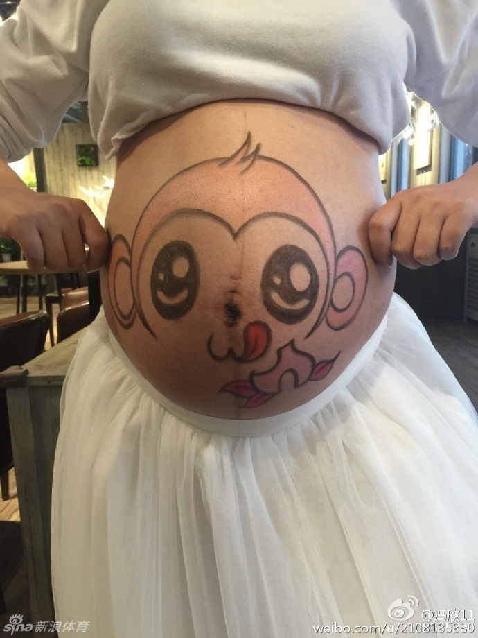 孕妈在江南风格的庭院中侧身而立，肚皮上的小猴子图案格外显眼，甜美的笑容与静谧的景色融为一体，完美诠释了“甜美写真”的主题。