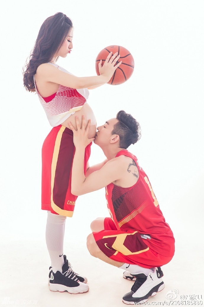 穿着球衣的冯欣从背后温柔环抱爱妻，两人一同轻抚绘有猴子图案的孕肚，仿佛在倾听未来宝宝的心跳，画面温馨而充满爱意。