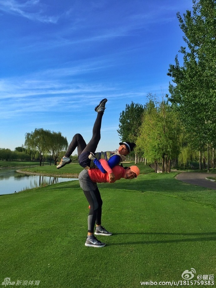 瞿颖与友人在球场开心互动，两人身影点缀在无垠绿茵中，显得格外惬意。