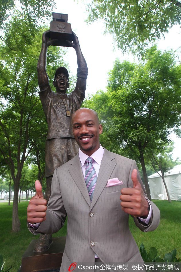 五棵松万事达中心南广场，马布里站在与自己等身高的铜像旁开怀大笑，铜像定格了他挥拳庆祝的经典瞬间，背后是湛蓝的天空