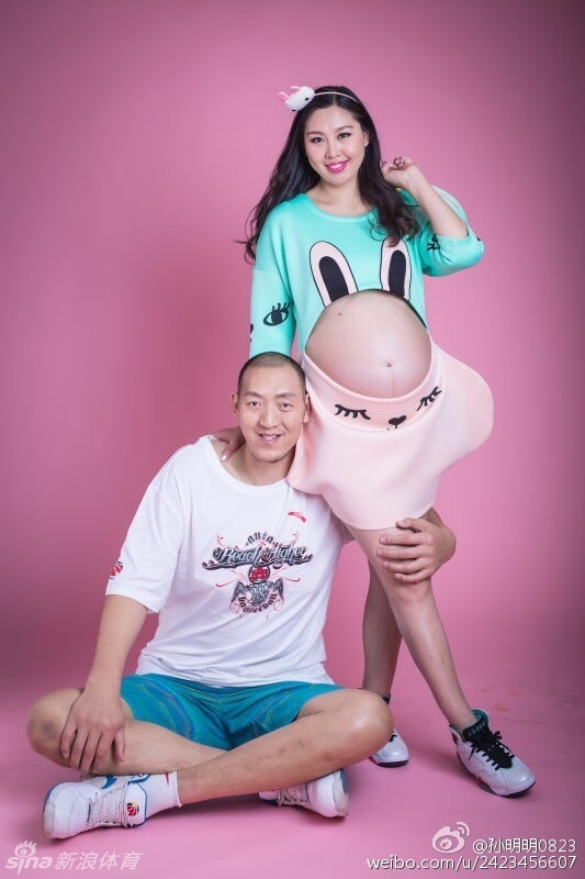 篮球巨人孙明明温柔地环抱爱妻，两人身穿休闲居家服，脸上的笑容如同午后阳光般灿烂温暖，满屏都是准父母迎接新生命的无限柔情。