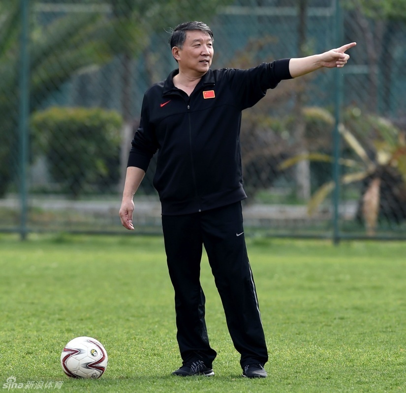 宫鲁鸣指导双手抱胸站在场边，眼神如炬紧盯着训练场上的每一次跑动，神情专注而严肃