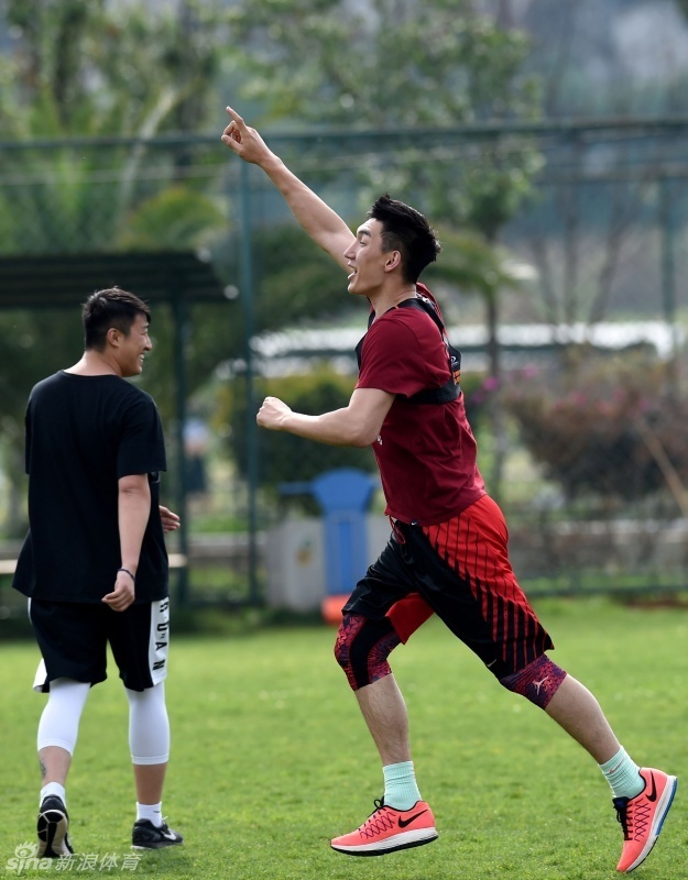 宫鲁鸣指导蹲在场边，手持战术板神情专注地向队员们布置战术，队员们围拢在他身边认真聆听