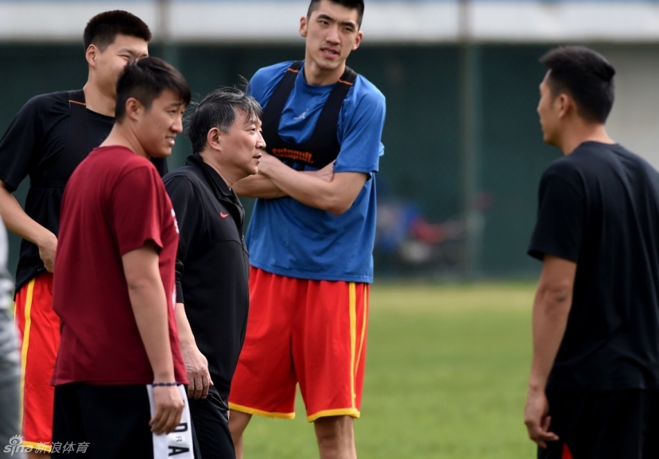 可兰白克坐在地上专注地进行腿部拉伸，李慕豪在一旁压腿，脸上带着轻松的笑意，气氛融洽