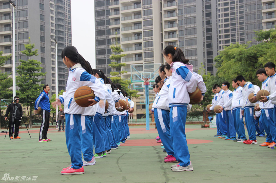 小队员在场上进行动作示范，李群站在身侧认真观察准备随时纠正细节