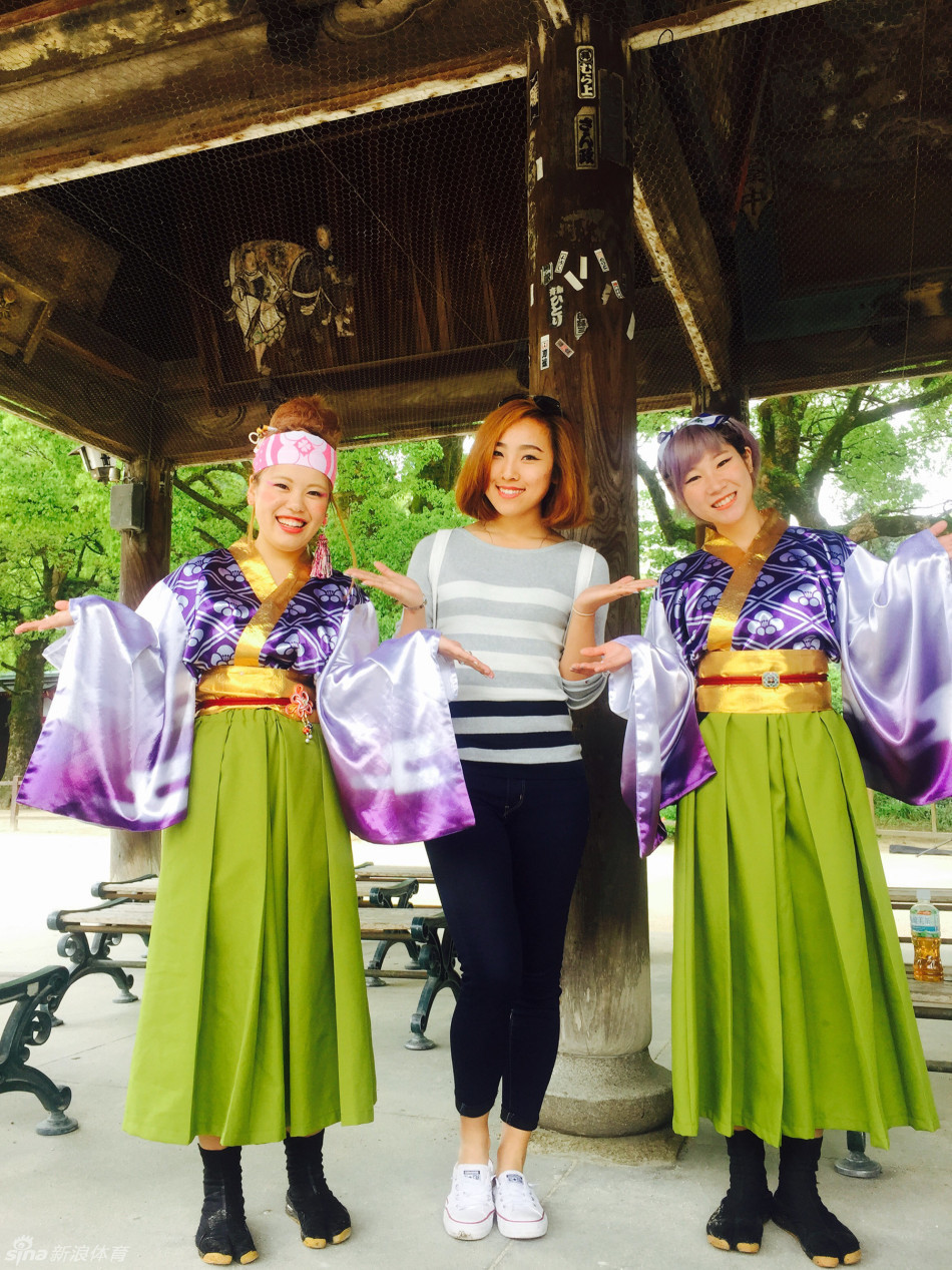 邮轮酒吧内灯光柔和，一位高大的球员亲切地搂着小球迷的肩膀，两人对着镜头比出胜利的手势，背景里是充满设计感的船舱内饰。