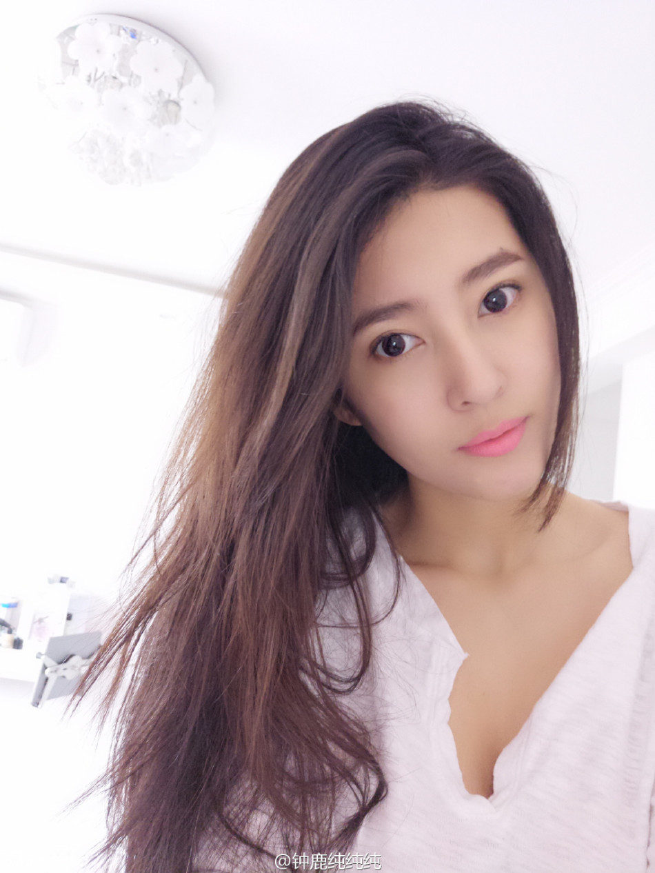 她坐在沙滩上，双手抱膝，温柔地注视着镜头，身后的海浪轻轻拍打着岸边，整个画面洋溢着清新与恬淡的气息，让人移不开眼。