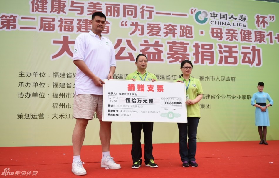 姚明双手紧握领跑旗，目光坚毅地望向远方，他身后的背景是蔚蓝的天空和整装待发的爱心跑者方阵，旗帜上的公益标语在阳光下格外醒目。