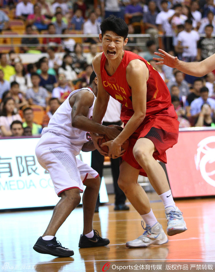 胡金秋在罚球线附近冷静出手投篮，面对扑防的加拿大球员，表情专注而稳定