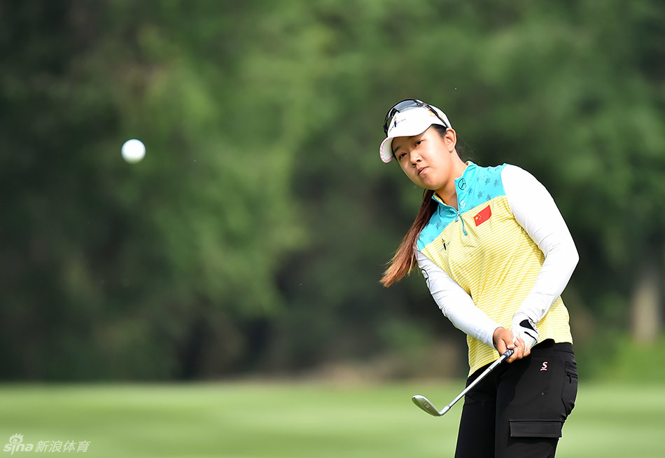 陶娟娟在成功推杆进洞后，紧握拳头示意庆祝，眼神中充满坚定与胜利的喜悦。