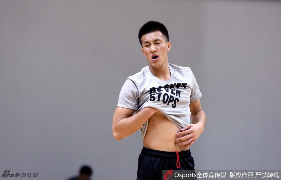 锋线悍将李根正在进行赛前的拉伸训练，他神情专注地压腿，每一块肌肉的延展都透露出职业球员对身体管理的极致追求。