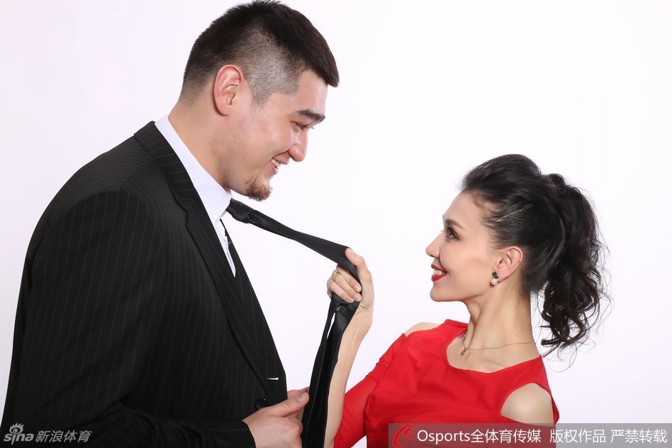 买尔丹毫不费力地将身穿婚纱的新娘轻轻抱起，新娘搂着他的脖子笑得灿烂如花，背景虚化的篮筐见证着这份刚柔并济的爱。